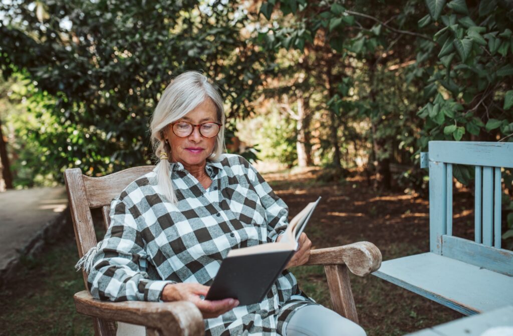 A senior with early dementia takes some afternoon downtime in memory care to read outdoors while enjoying the weather