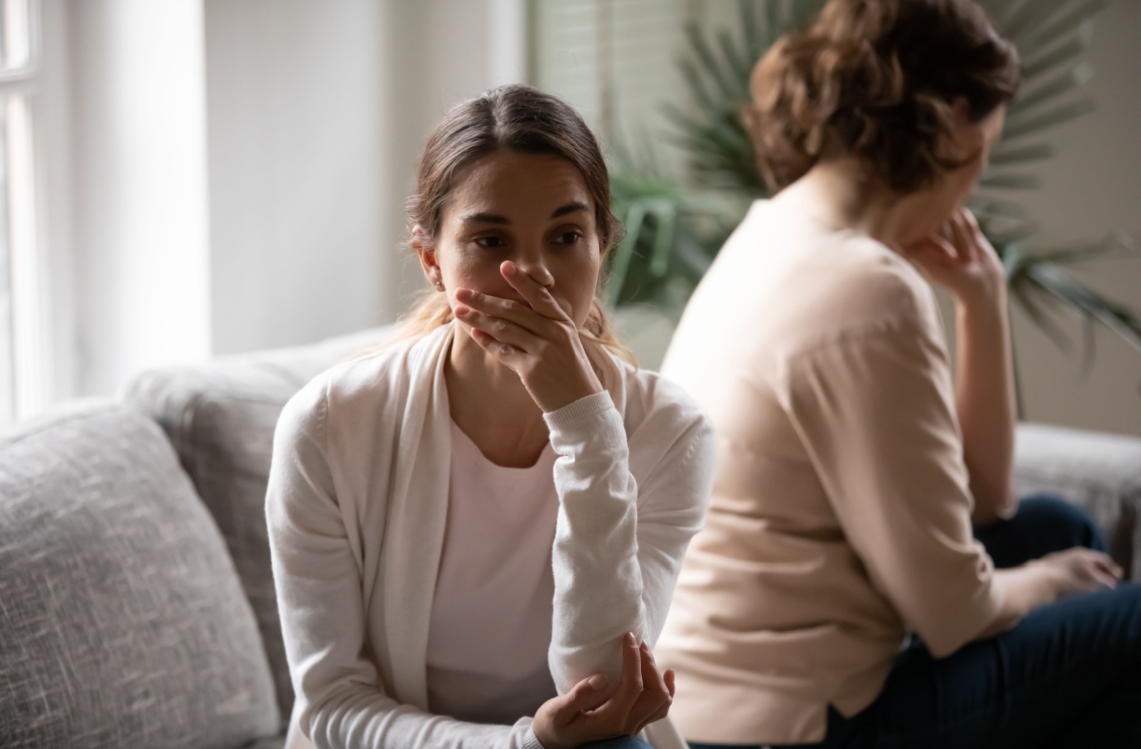 A distraught adult sits with their back to their older parent with dementia, worried about having said the wrong thing