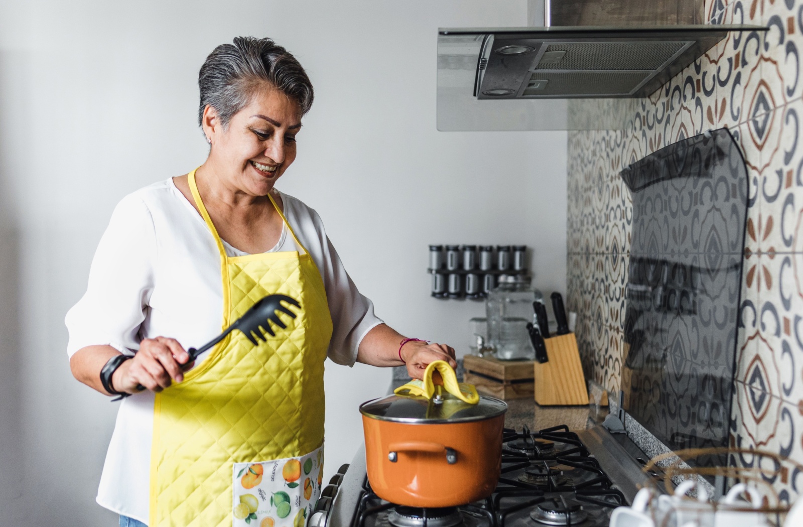 A senior cooks a meal on a stovetop in their independent living apartment